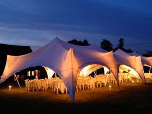 Evening marquee with warm interior lighting and round dining tables