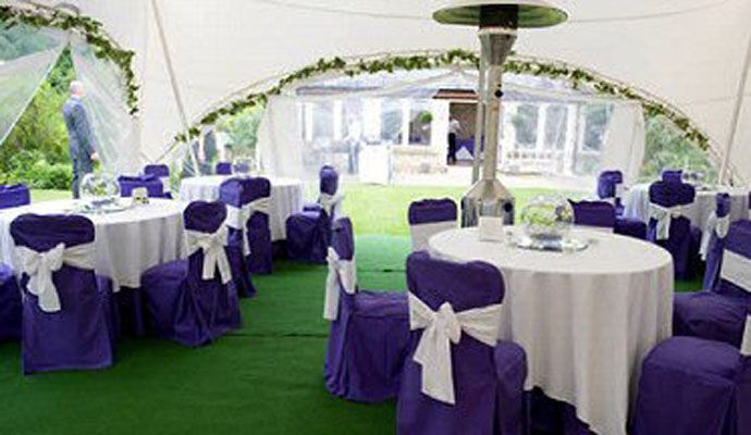 Inside a decorated marquee with purple chair sashes and floral table centres