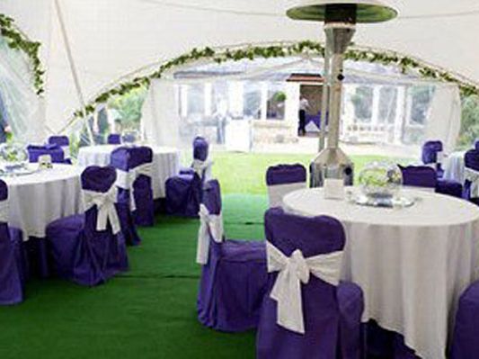 Inside a decorated marquee with purple chair sashes and floral table centres