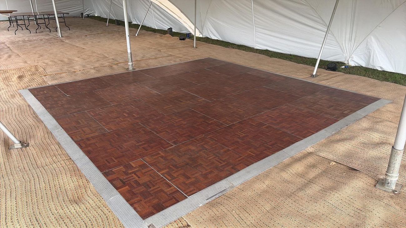 Dance floor installed on matting inside a Capri marquee during setup